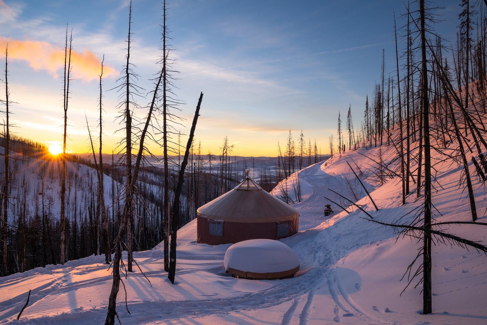 Alpine Yurt at sunrise with skis stacked outside in Montana's Swan Mountains