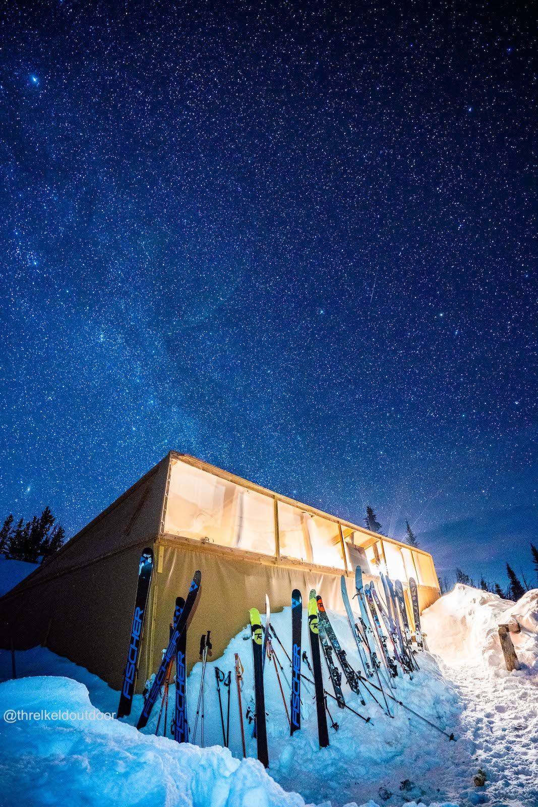 Big Belt Hut under the stars at night with skis lined up outside